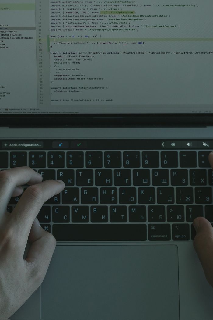 Services Hands typing on a laptop with a visible coding interface, showcasing technology use.