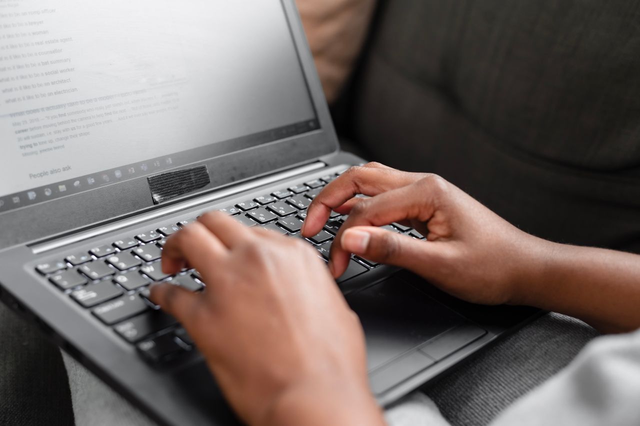 Services Close-up of hands typing on a laptop keyboard, working from home setting.