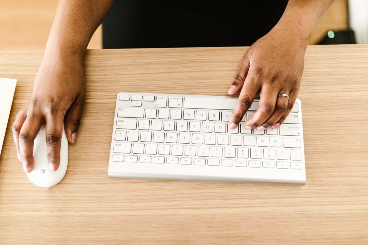 Services Hands typing on a white keyboard on wooden desk, ideal for business or tech themes.